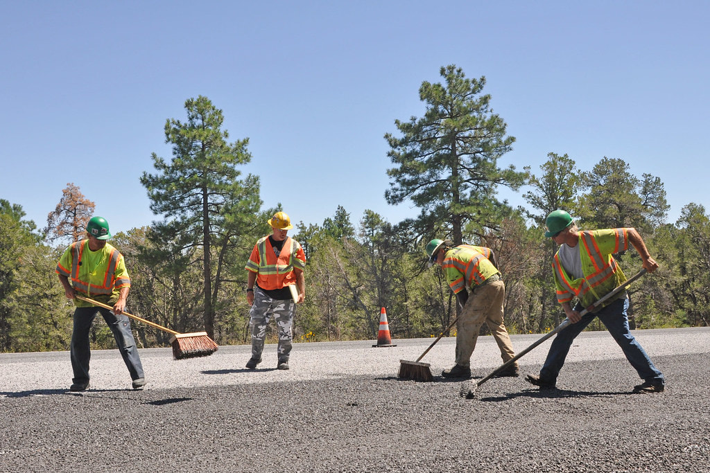 Construction workers leveling fresh asphalt on ground to pave a smooth new road