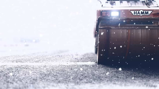 Asphalt paver heavy machinery paving asphalt in the snow